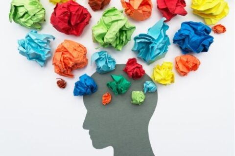 Silhouette of a person's head with many pieces of colorful, crumpled tissue paper blooming out of it