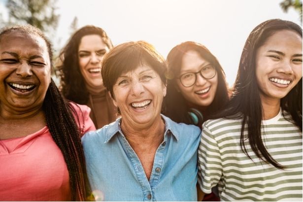 A group of women of different ages and cultural backgrounds smiling at the camera