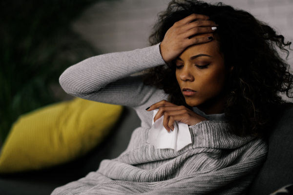 Sick woman at home. Young african woman laying on sofa she is sick having fever.