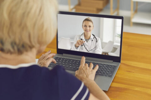 Senior woman sitting at laptop and talking to virtual doctor of e-health service