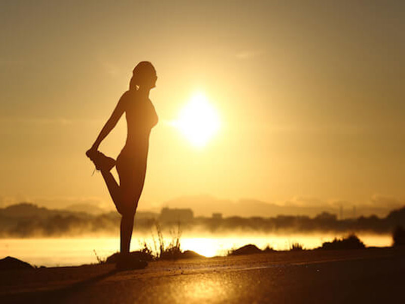 a woman exercising during the sunrise