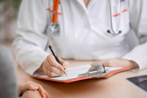 doctor writing on paper in front of client