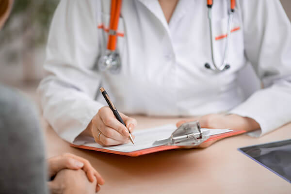 doctor writing on paper in front of client