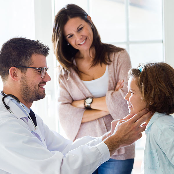 Mother with her daughter having throat examination by pediatrician in the office