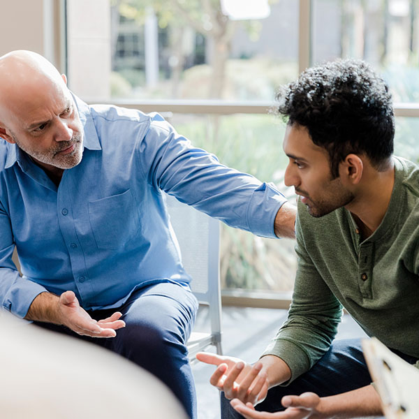 Mature man helps younger man verbalize problems in therapy