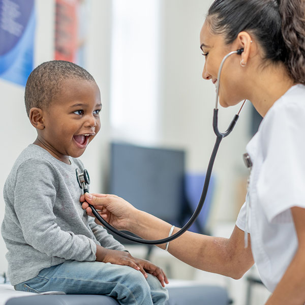 sweet little boy sits up on an exam table in a doctors office