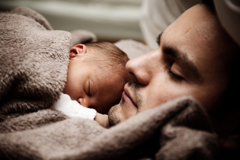 Infant child sleeping on man