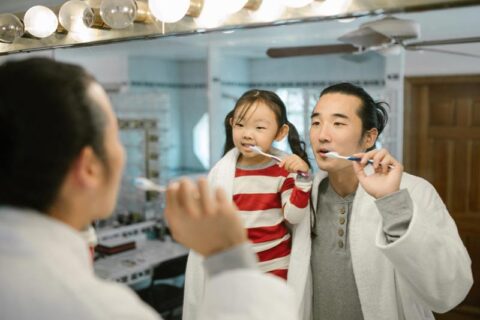 man and child brushing their teeth