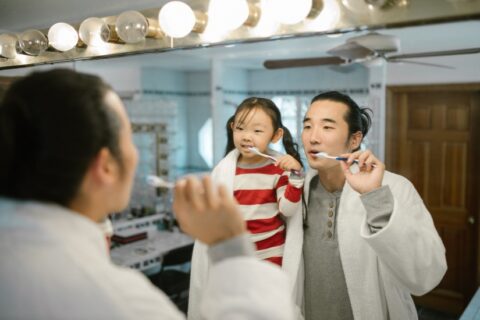 Girl washing her teeth along with her dad