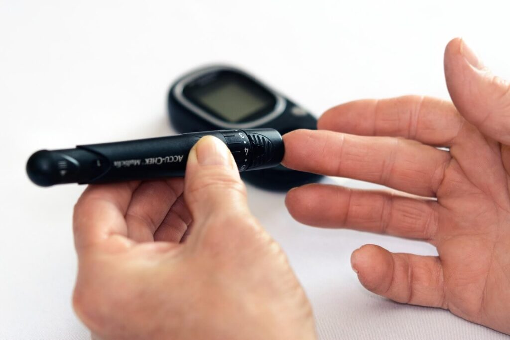 person testing sugar level with a blood sugar machine