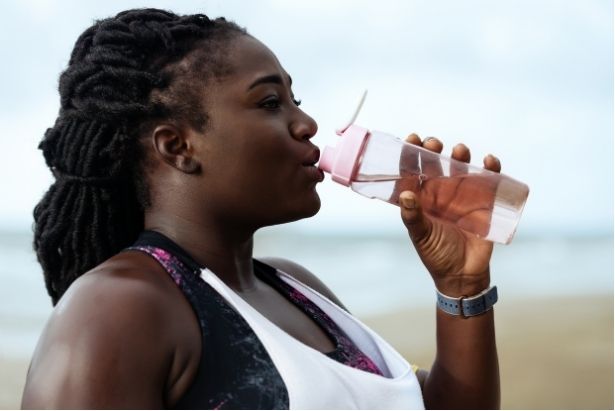 a woman drinking water from a plastic water bottle