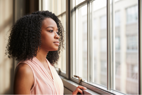 woman looking out a window with a thoughtful expression