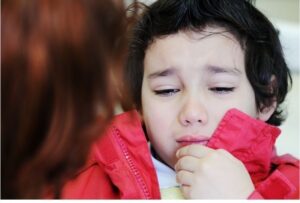 A male child looking distressed and holding his hand to his mouth