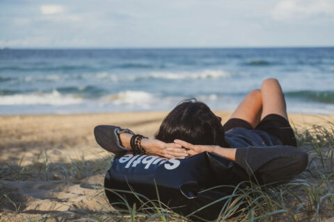 A person lying on grass next to a beach enjoying the benefits of rest.