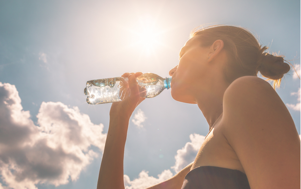 Woman outside drinking water from a clear bottle