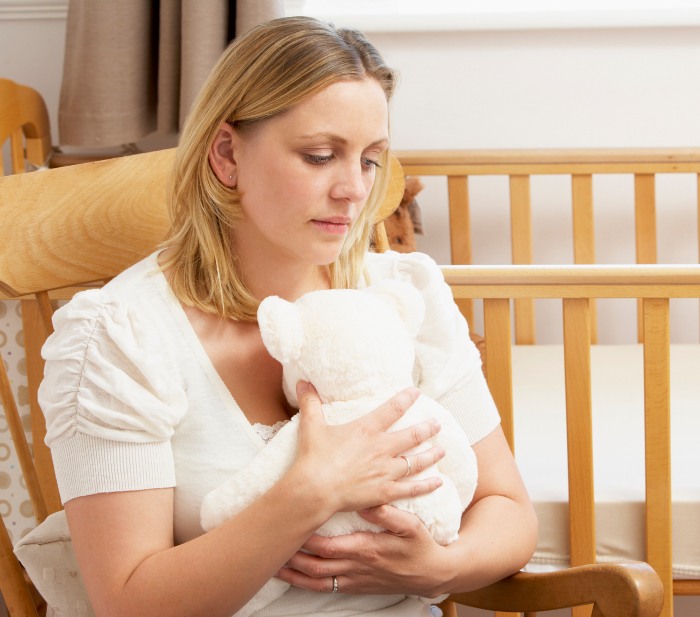 Sad & Depressed Woman hugging a bear after Miscarriage