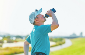 A man drinking water on a golf course