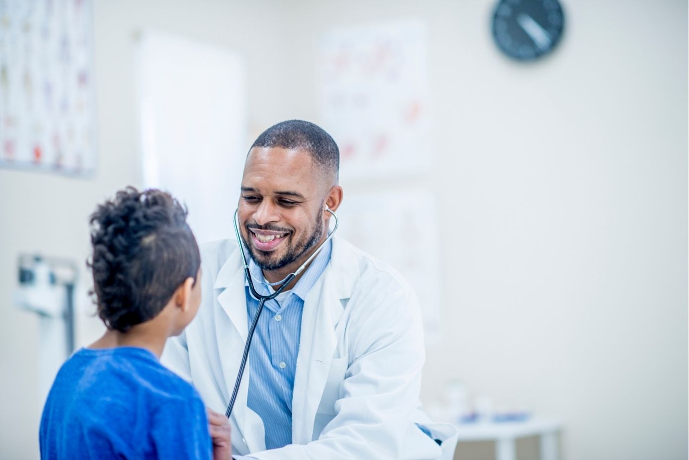 Clinician in white coat listening to a patients heart