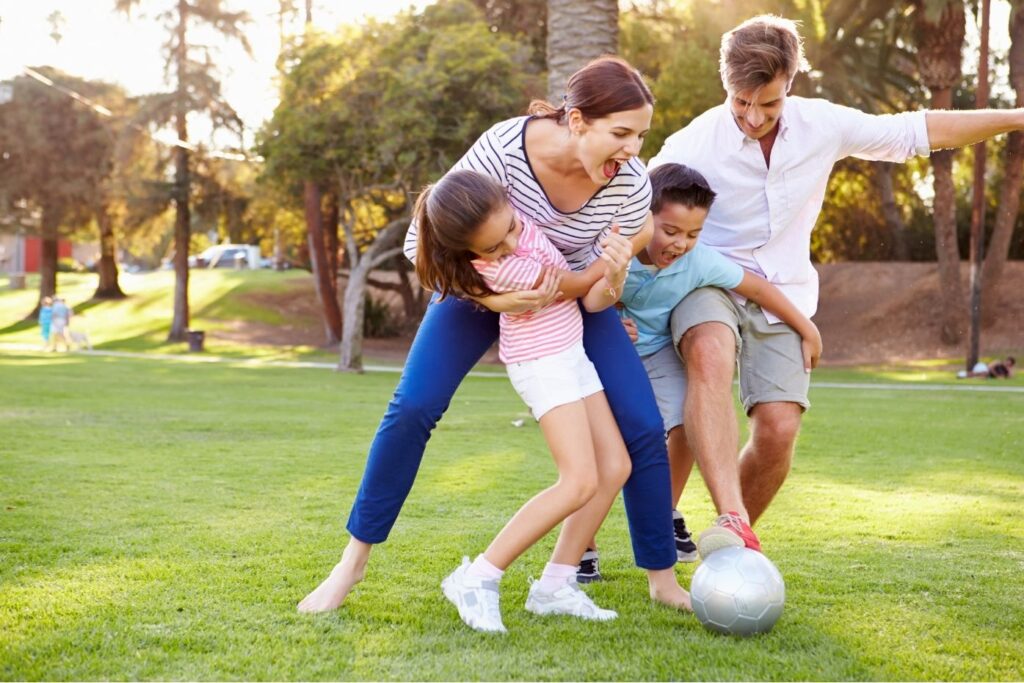A family of four playing soccer outside