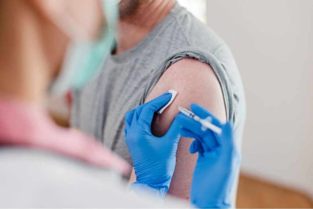 A man with his sleeve rolled up getting a flu shot