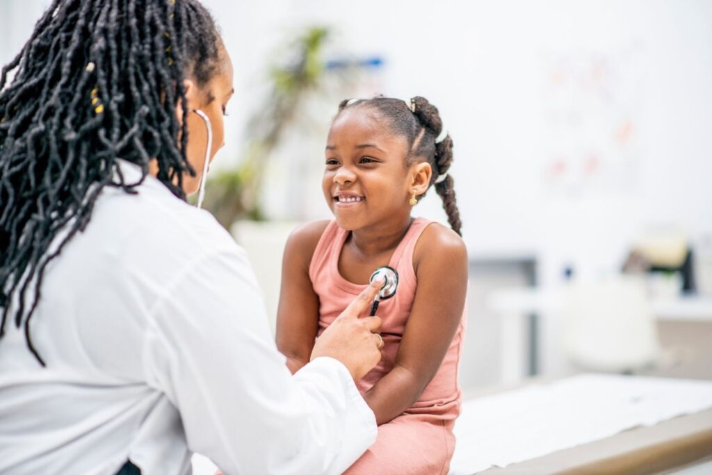 A pediatrician listening to a young girl's heart