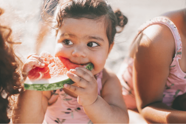 A little girl eating a slice of watermelon at a beach in Brevard County, FL

