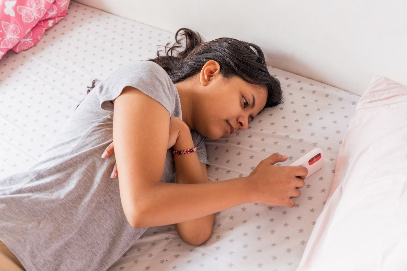 Young girl relaxes in bed with remote, enjoying a cozy AI moment in Brevard County, FL