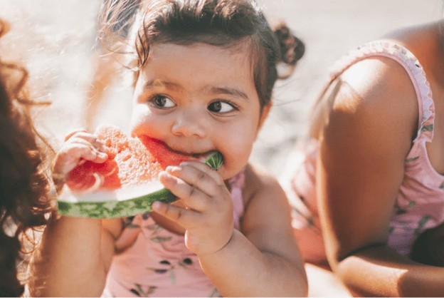 Little girl enjoying a slice of watermelon, a healthy snack, in Brevard County, FL