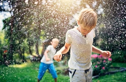 Two children joyfully playing Water Balloon Games in the rain in Brevard County, FL
