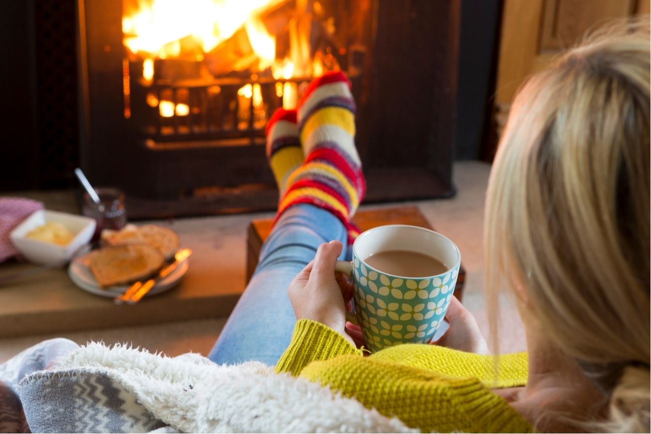A woman sitting in front of a fire with cocoa