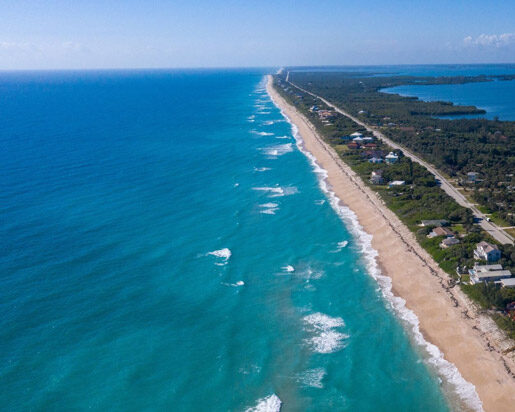Aerial view of a narrow beach coastline with houses along the shore.