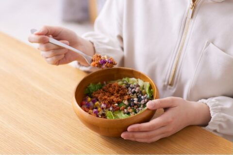 Woman eating a bowl of vegetables and legumes