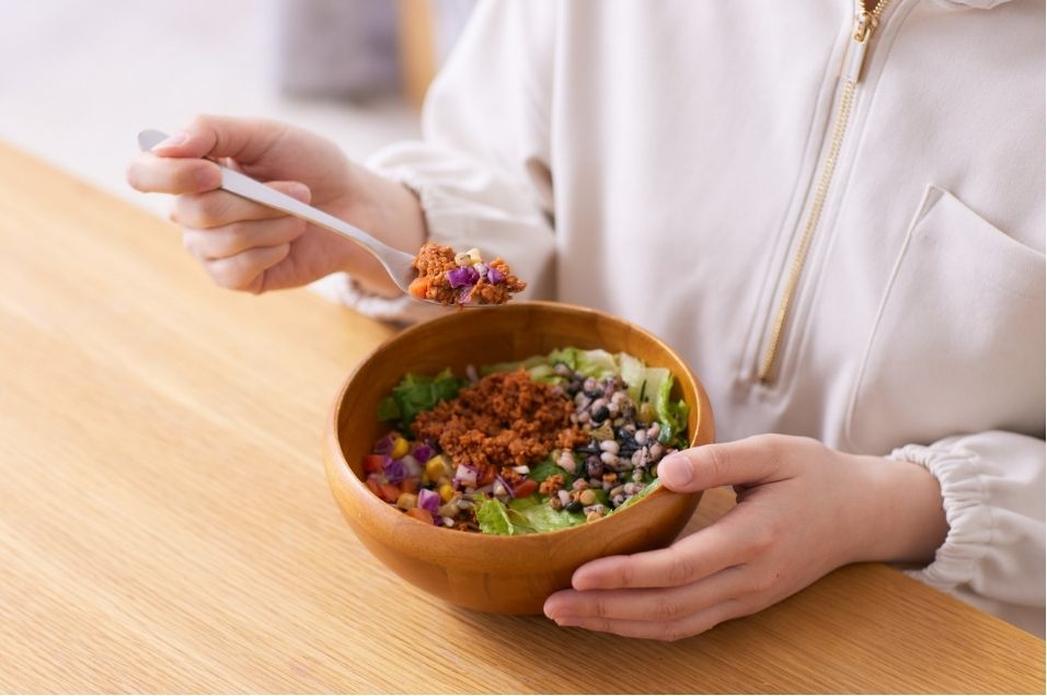 Woman eating a bowl of vegetables and legumes